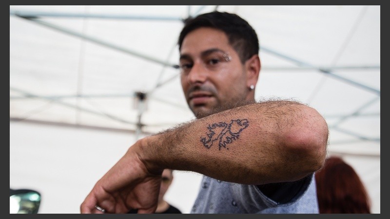 Un hombre muestra un tatuaje recién hecho de Malvinas. Se hacen gratis en una de las carpas.