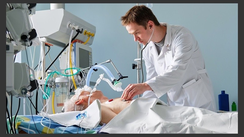 Intensive care caucasian doctor examines intubated critical stance patient writing notes to case report in intensive care department